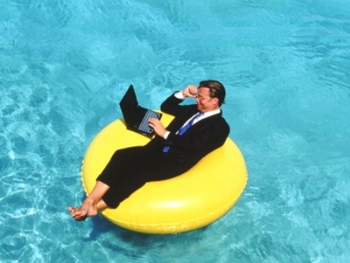 мужик в костюме и ноутбуков плавает в бассейне на подушке