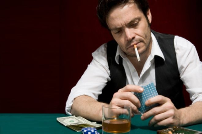 Брутальный мужчина играет в карты под сигарету и стакан виски