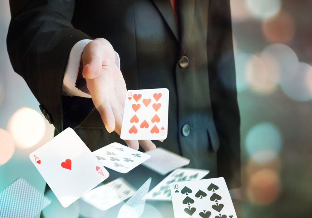 Рука мужчины в строгом костюме бросает игральные карты