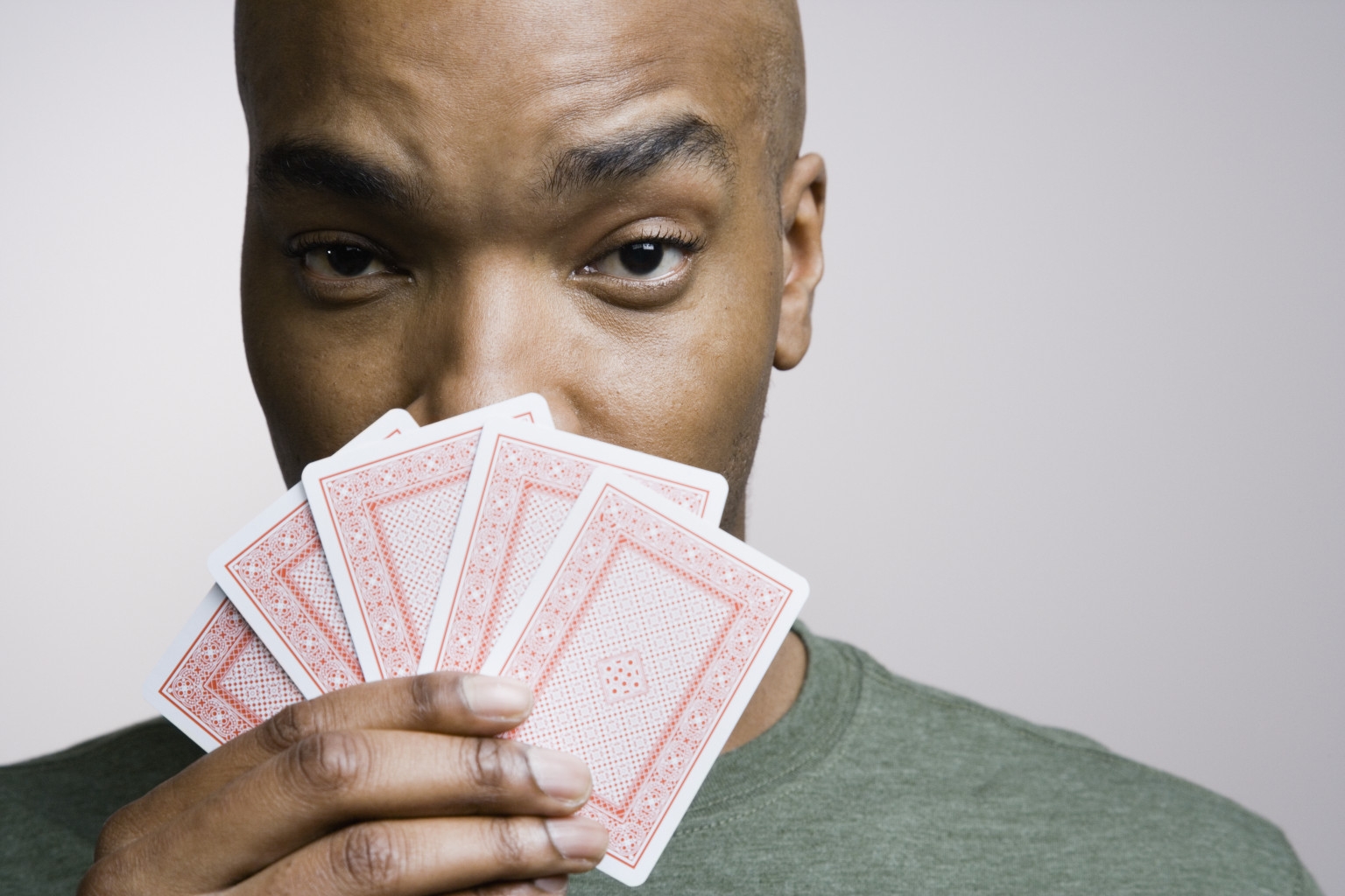 Афроамериканец прячет половину лица за веером из карт