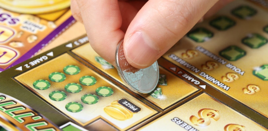 Игрок стирает монеткой защитное поле на лотерейном билете