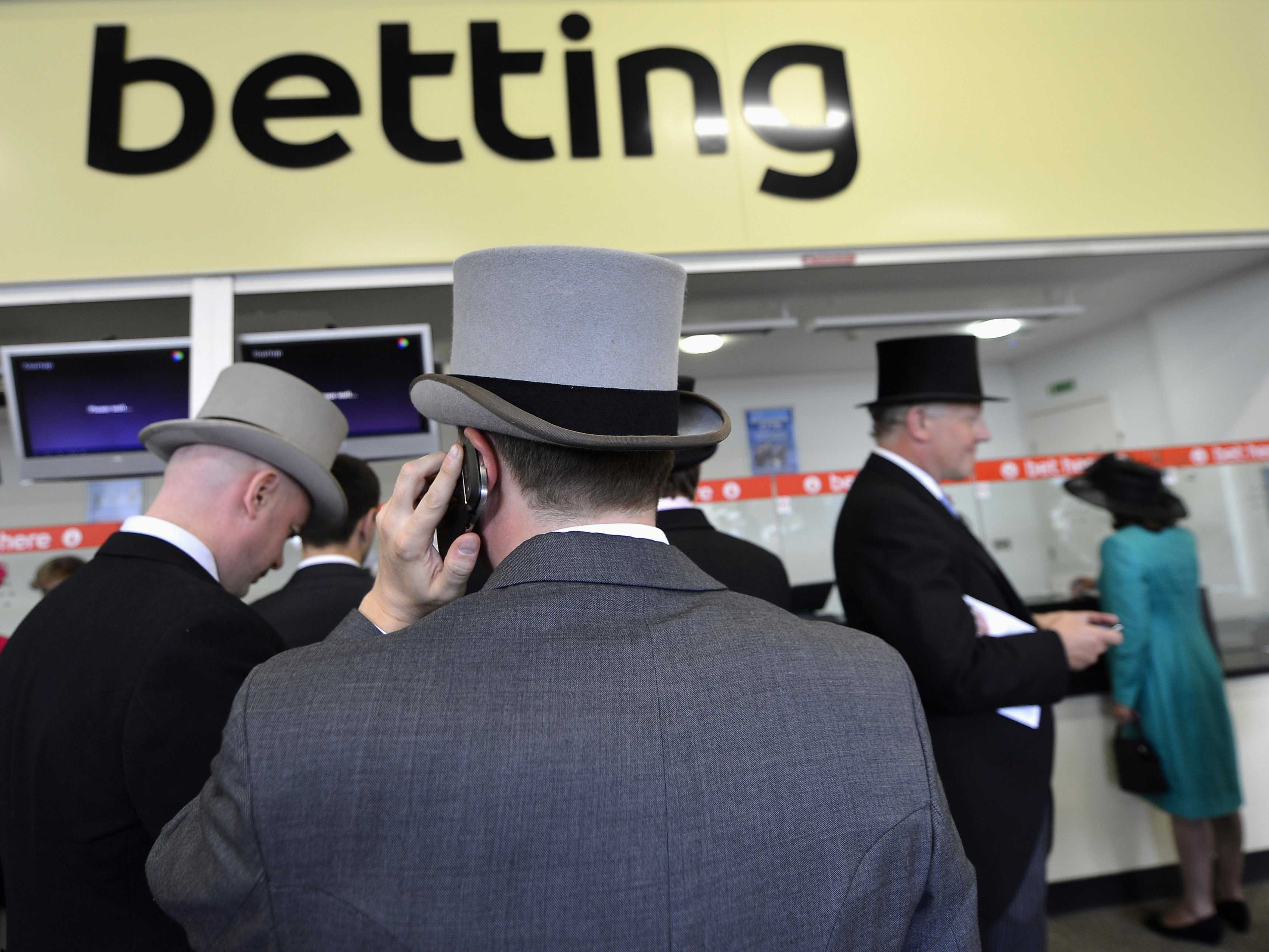 Надпись "betting" и спины игроков на ставках в зале букмекерской конторы