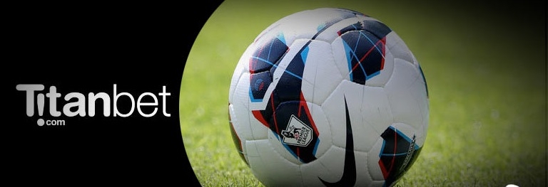 Фирменная надпись "Titanbet" и футбольный мяч на поле крупным планом