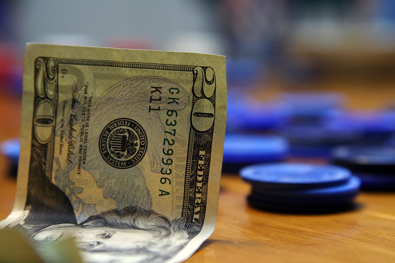 На столе лежат двадцать долларов и фишки казино