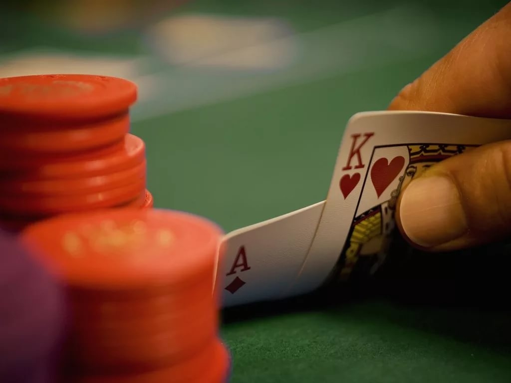 Рука, приподнимающая две карты, и стопка оранжевых фишек