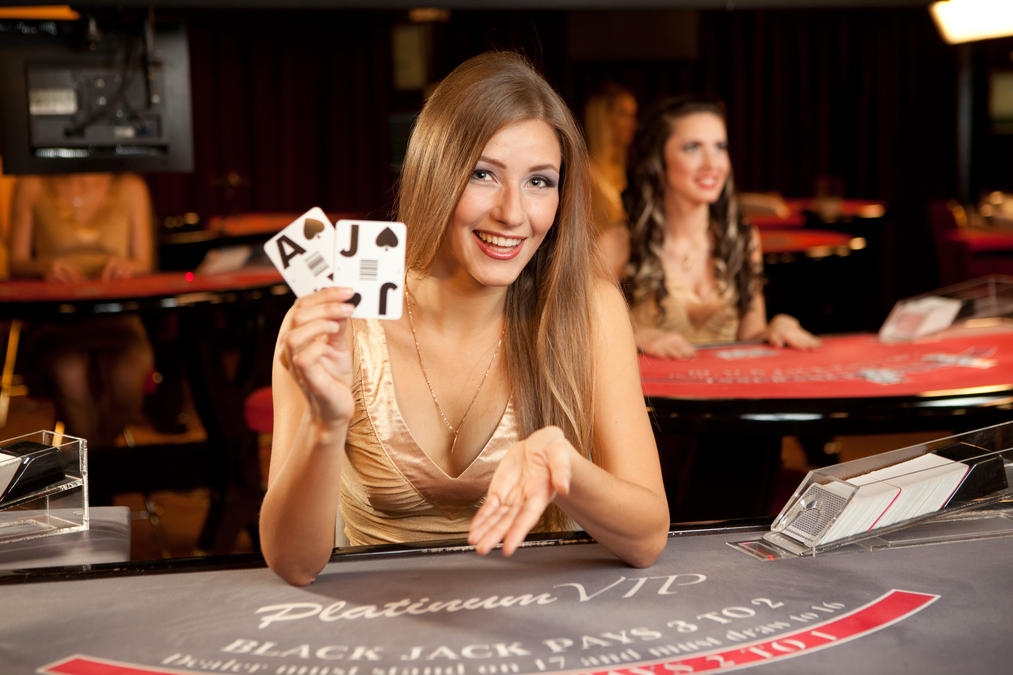 Русоволосая красотка-крупье ждет игрока за столом для блэкджека