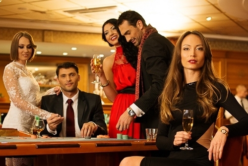 Три красотки в вечерних платьях пьют шампанское и наслаждаются игрой в рулетку в компании двух восточных мужчин