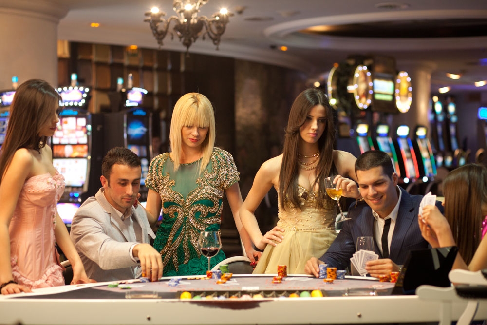 Молодые мужчины и их привлекательные спутницы играют в покер в дорогом казино