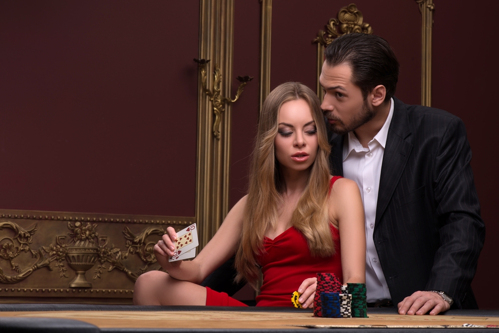 Мужчина заигрывает к своей сексуальной спутнице, сидя за столом для покера