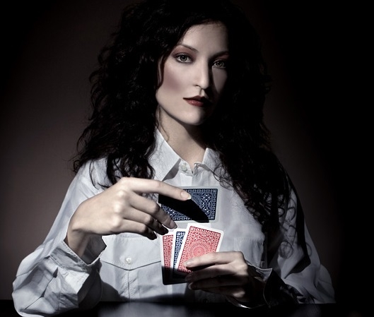 Загадочная темноволосая девушка с отстраненным взглядом и с картами в руках