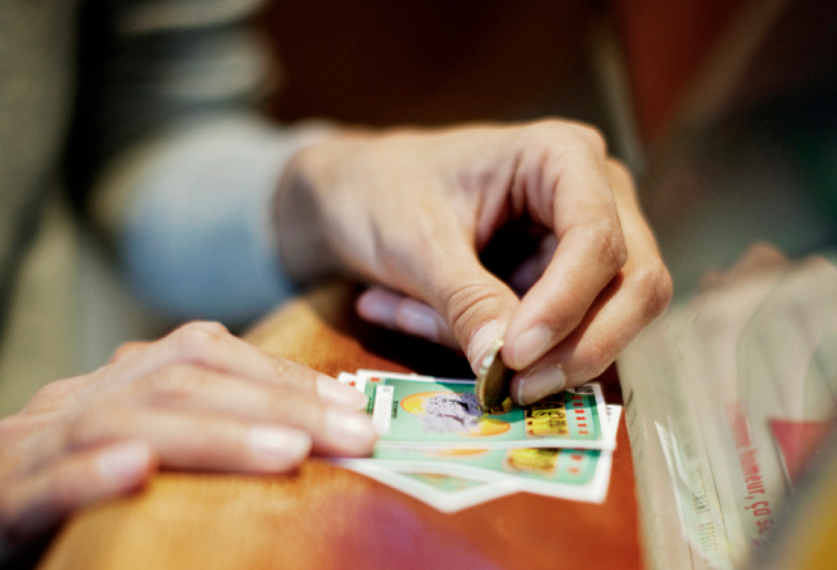 Руки игрока, стирающие защитное поле на скретч-карте