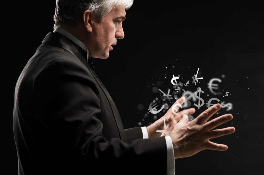 Зрелый мужчина стоит в профиль, выставив руки, вокруг которых вращаются символы разных валют мира