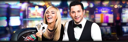 Блондинка смеется, демонстрируя карты, а ее напарник молодой крупье загадочно улыбается