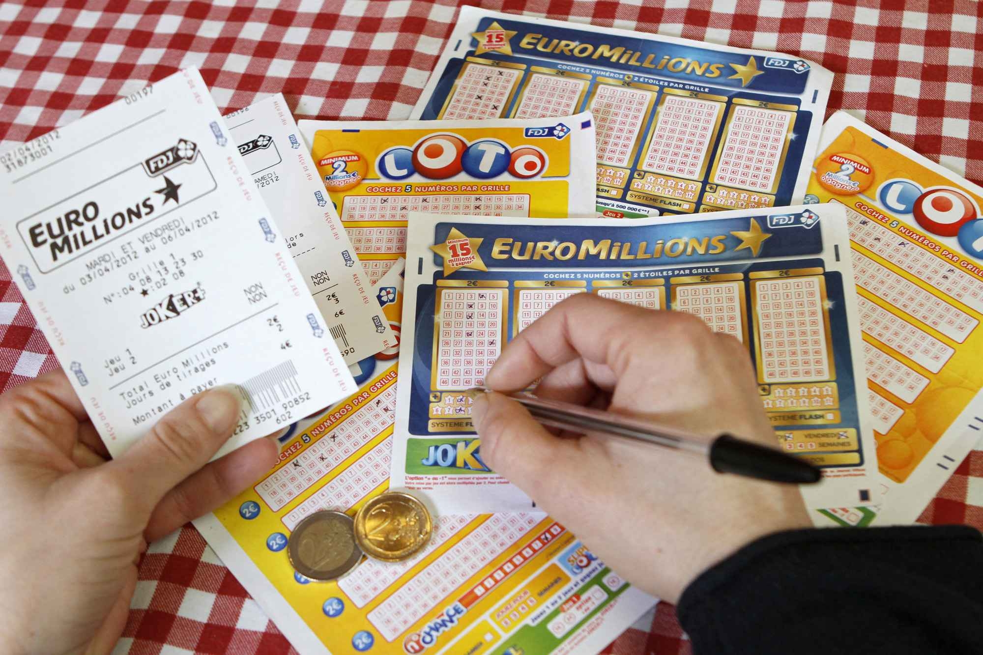 Руки игрока, заполняющего лотерейные билеты EuroMillion и SuperLotto