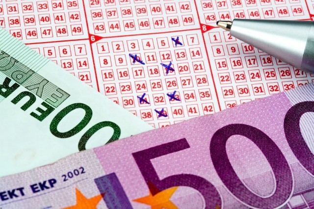 Поле лотерейного билета, на котором лежат купюры евро и ручка