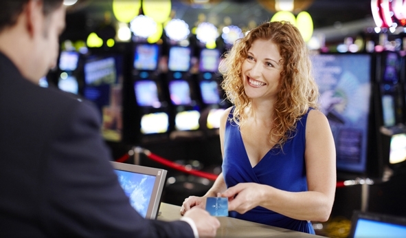 Привлекательная клиентка улыбается работнику казино, протягивая свою карту