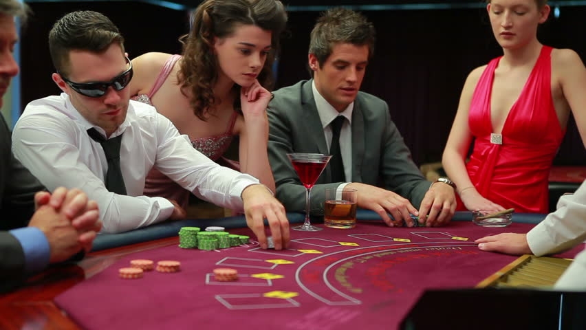 Серьезные мужчины ведут игру в блщэкджек, а девушки в откровенных нарядах наблюдают за игорным столом