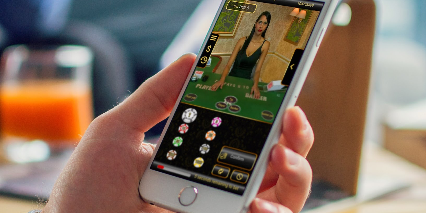 Игрок держит смартфон, на котором открыта игра с живым дилером