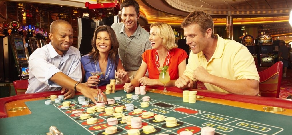 Азартные мужчины и женщины выпивают и веселятся за игрой в рулетку