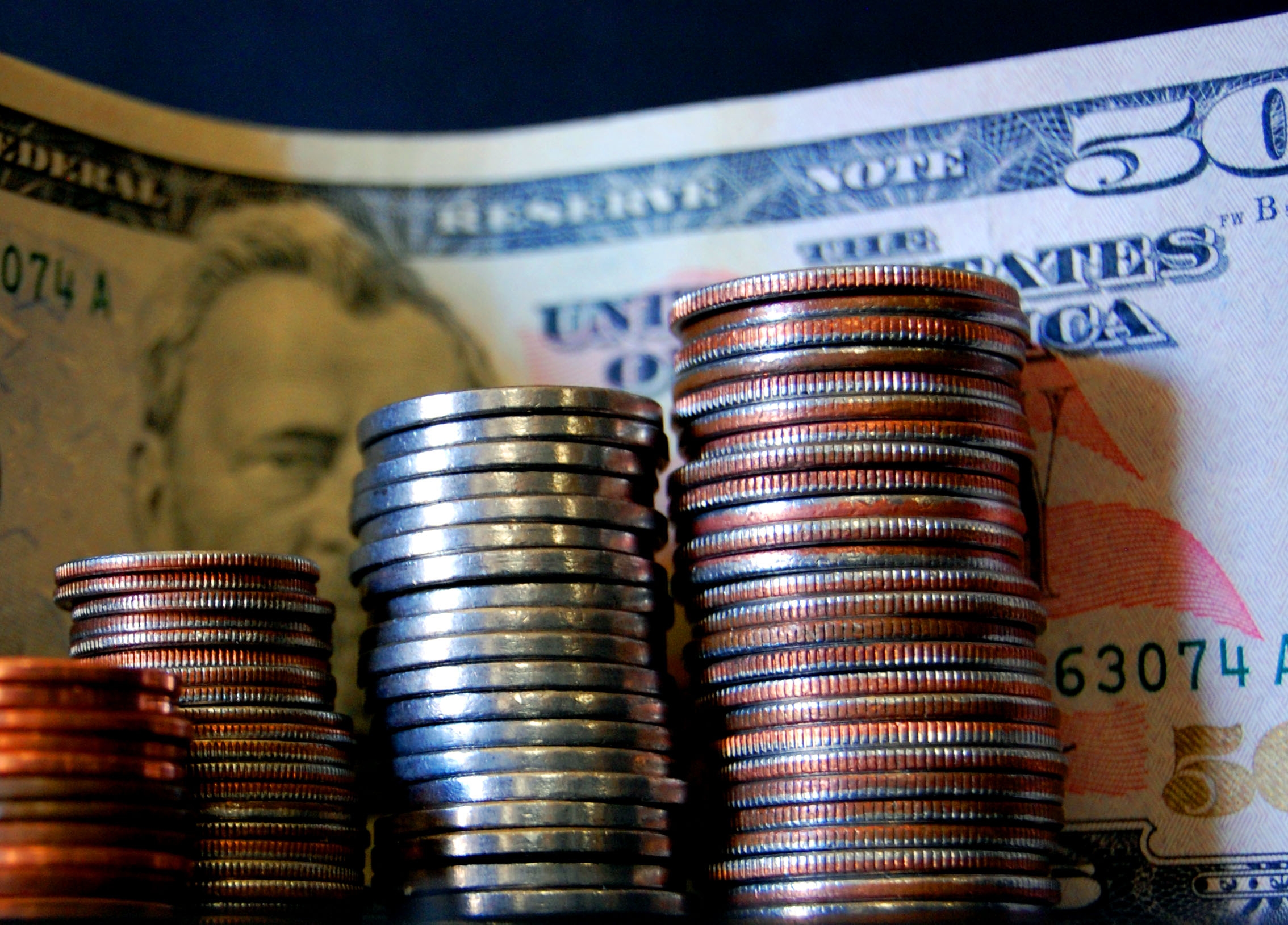 Четыре стопки центов, выставленные рядом с купюрой номиналом в пятьдесят долларов