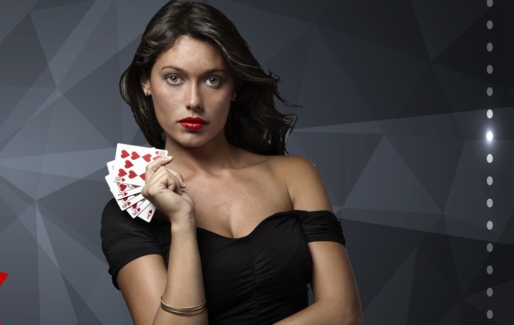 Привлекательная брюнетка в обтягивающем черном платье позирует с картами червовой масти в руках