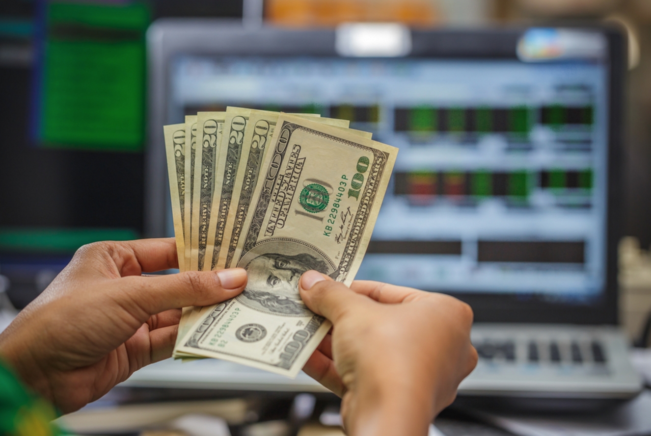 Купюры по двадцать евро в руках трейдера на фоне раскрытого ноутбука