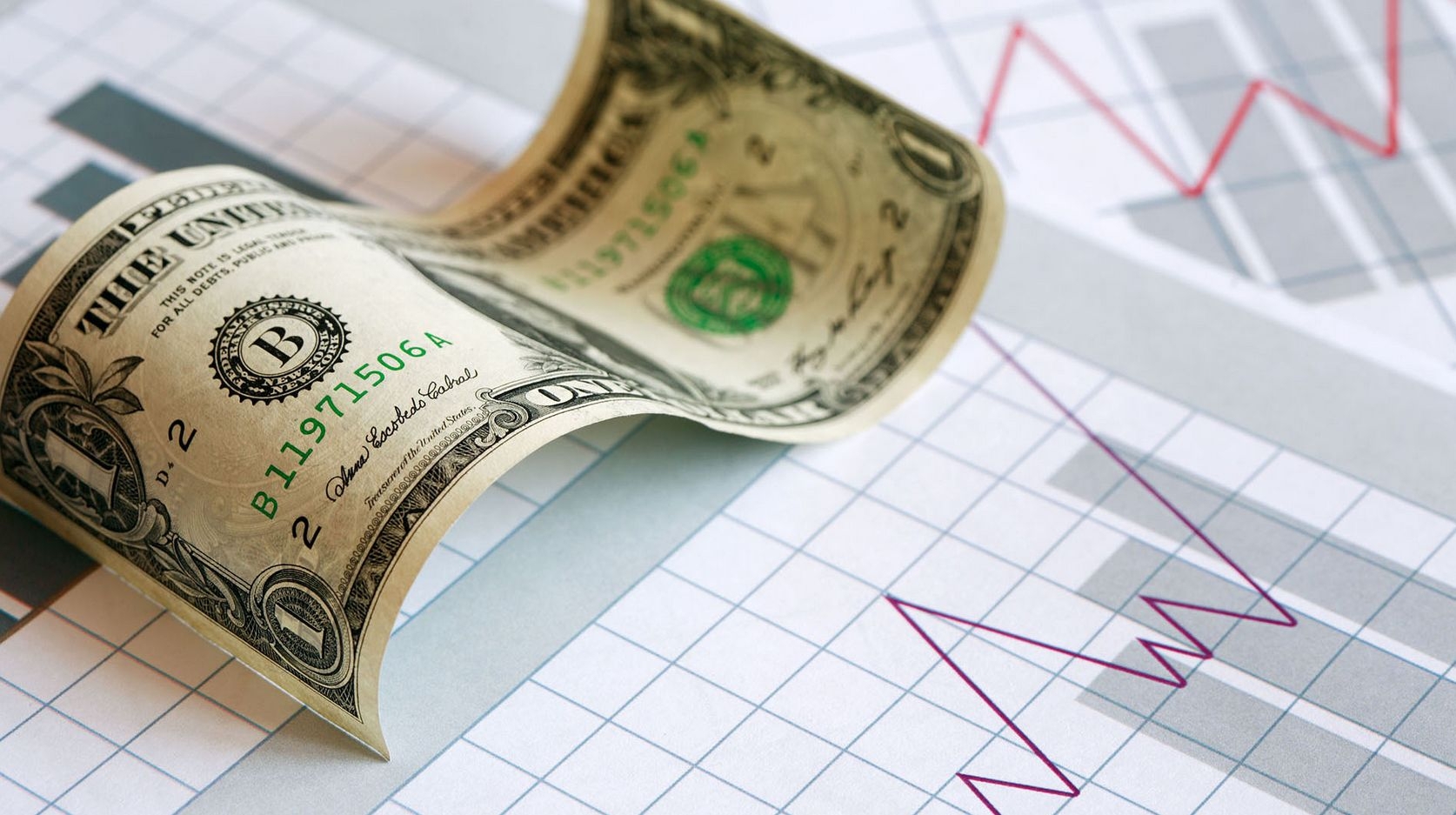 Купюра номиналом в один доллар лежит на листе из графиком