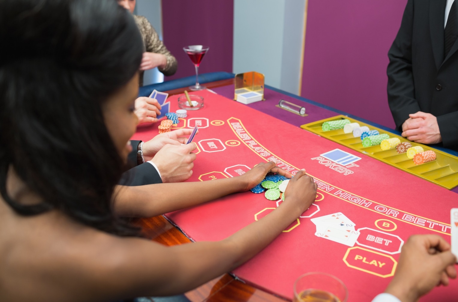 Молодая стройная мулатка совершает ставку в покере, играя против крупье