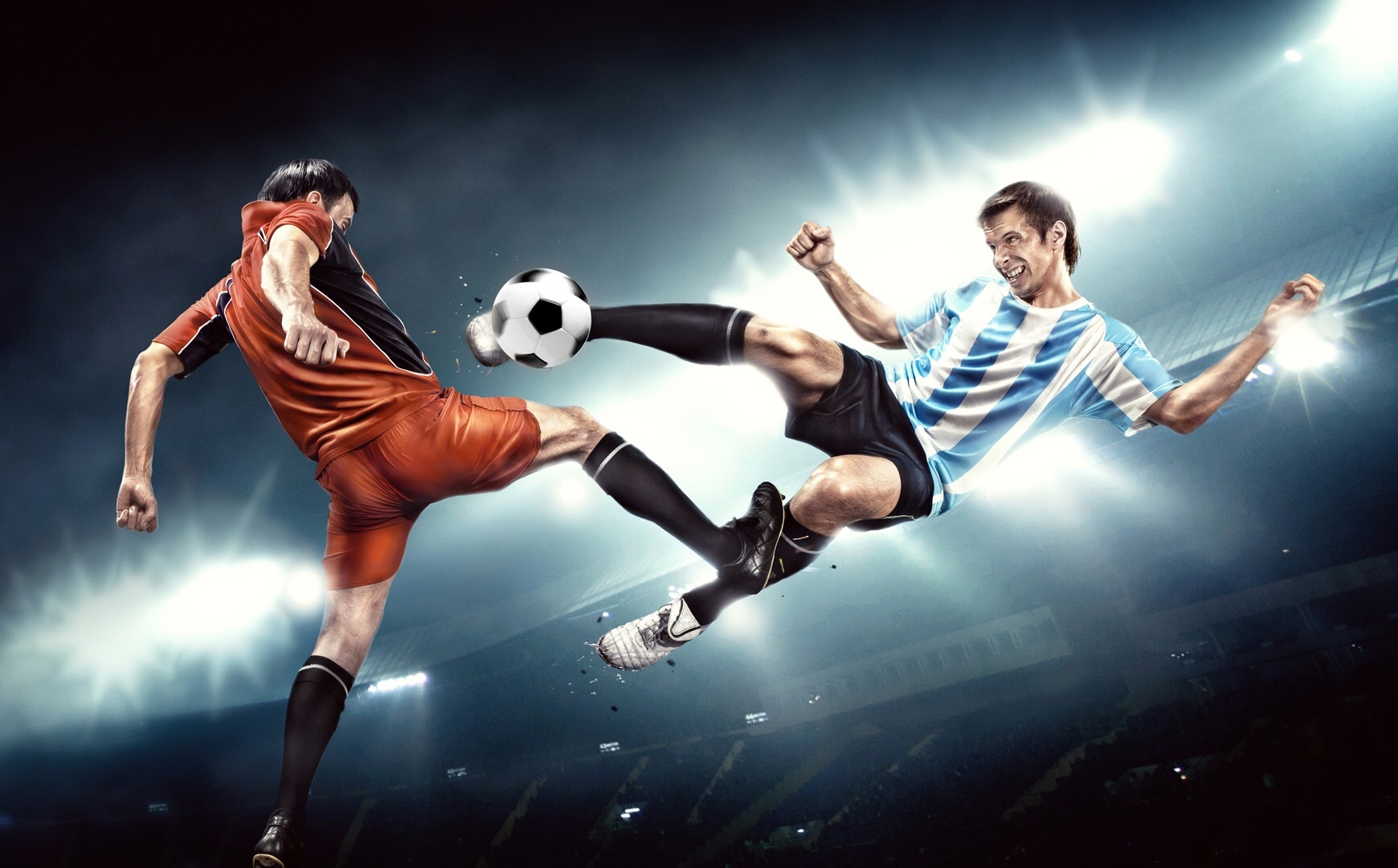 Двое футболистов сражаются за мяч в прыжке в полутьме