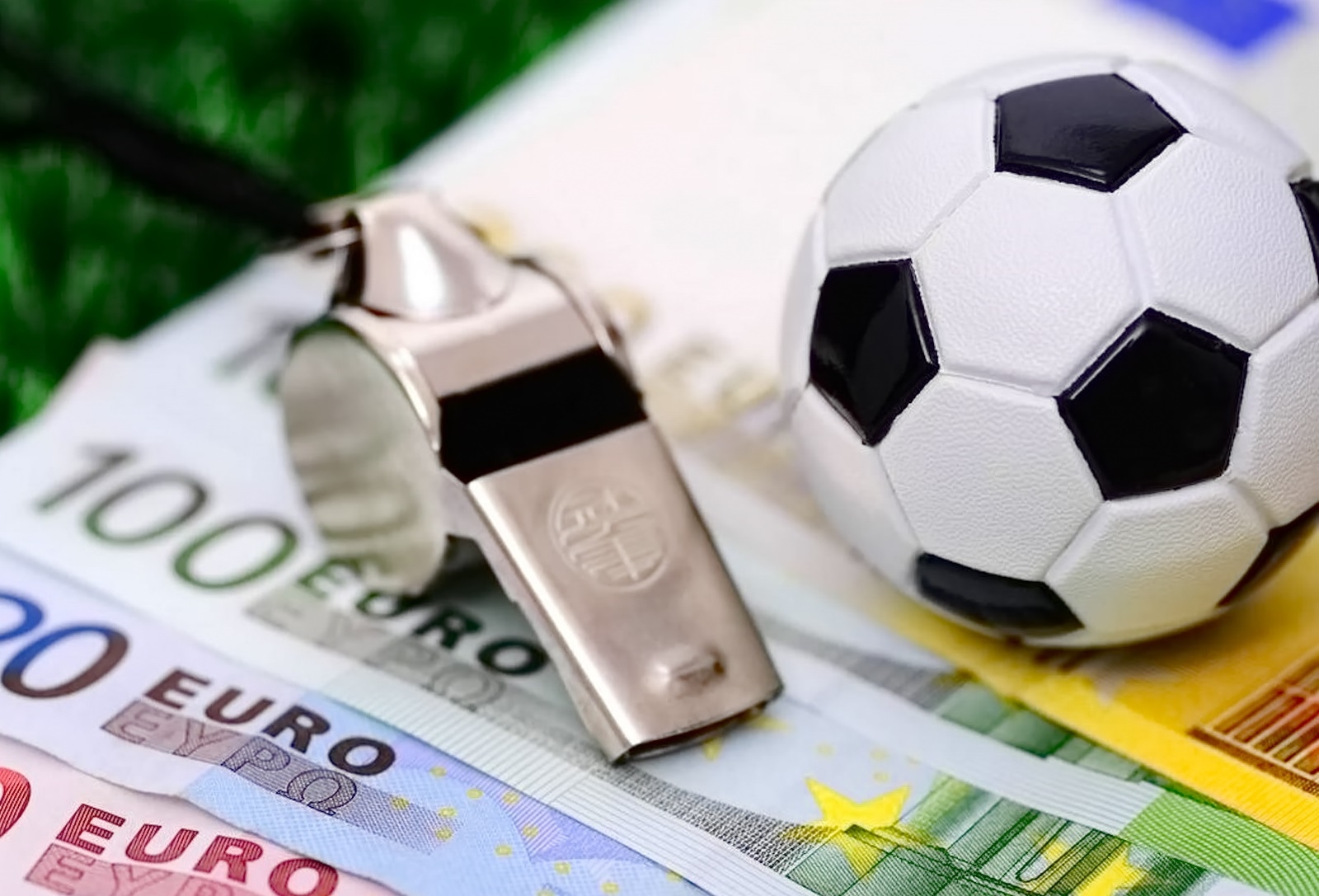 На веере из купюр евро лежит свисток и маленький футбольный мяч