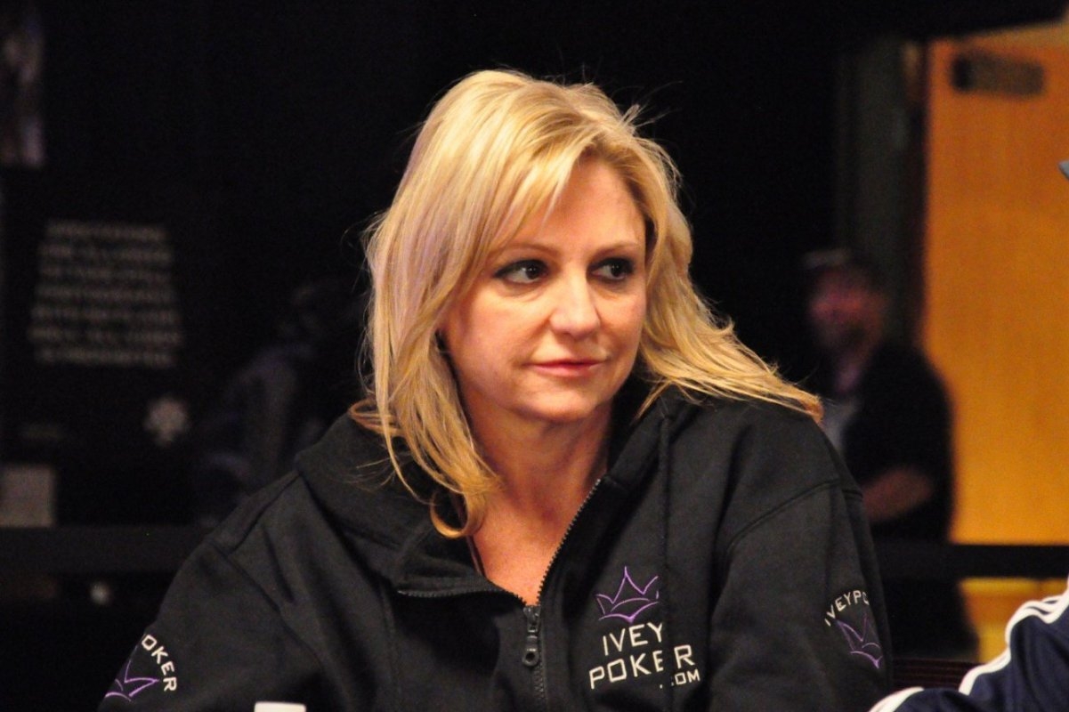 Дженнифер Харман смотрит всторону, сидя за столом для игры в покер