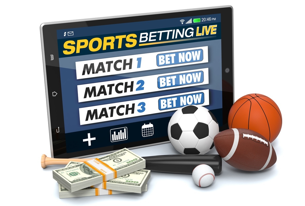 На планшете открыт сайт букмекерской конторы, а рядом лежат мячи для регби, футбола, американского футбола и баскетбола, а также пачки стодолларовых купюр