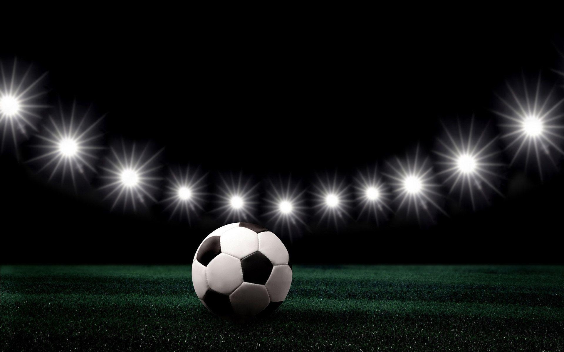 На дворе ночь, футбольным мяч лежит на поле при свете софитов