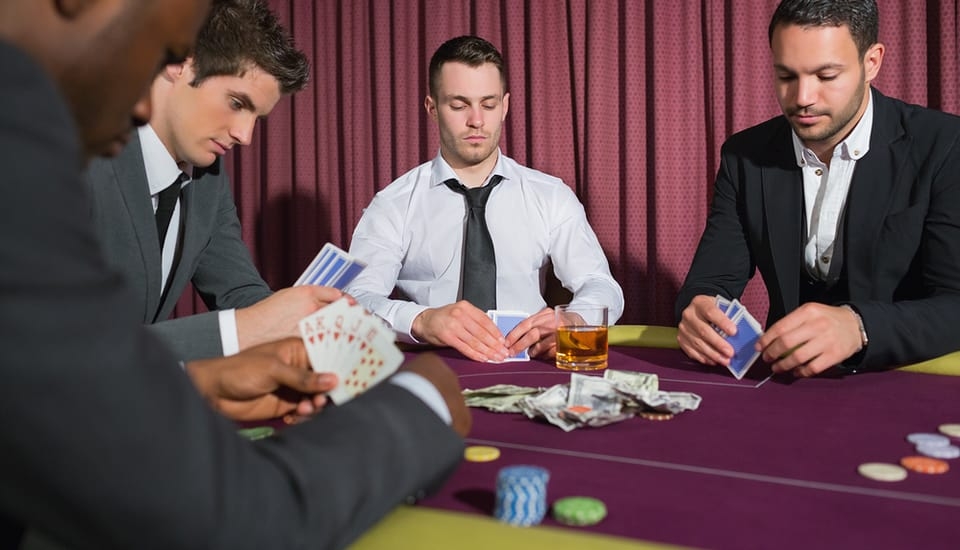 Четверо молодых успешных мужчин играют в покер, распивая алкоголь