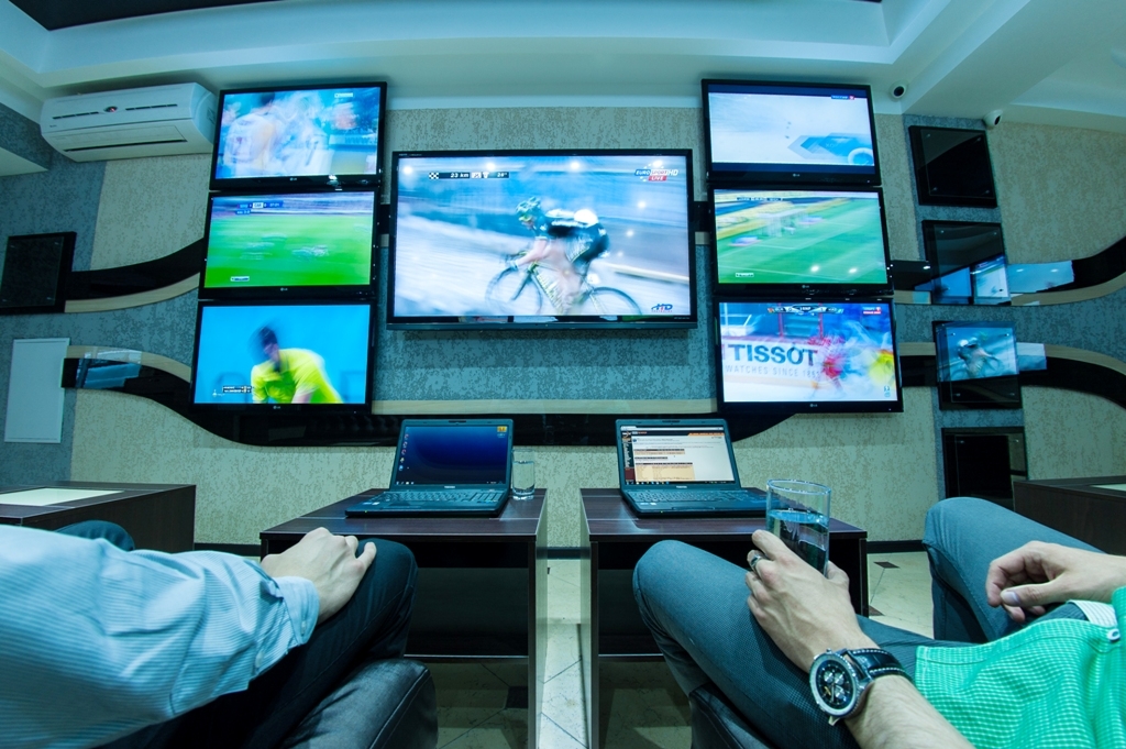 Мужчины расслабляются за просмотром спортивных матчей, на которые совершили ставки