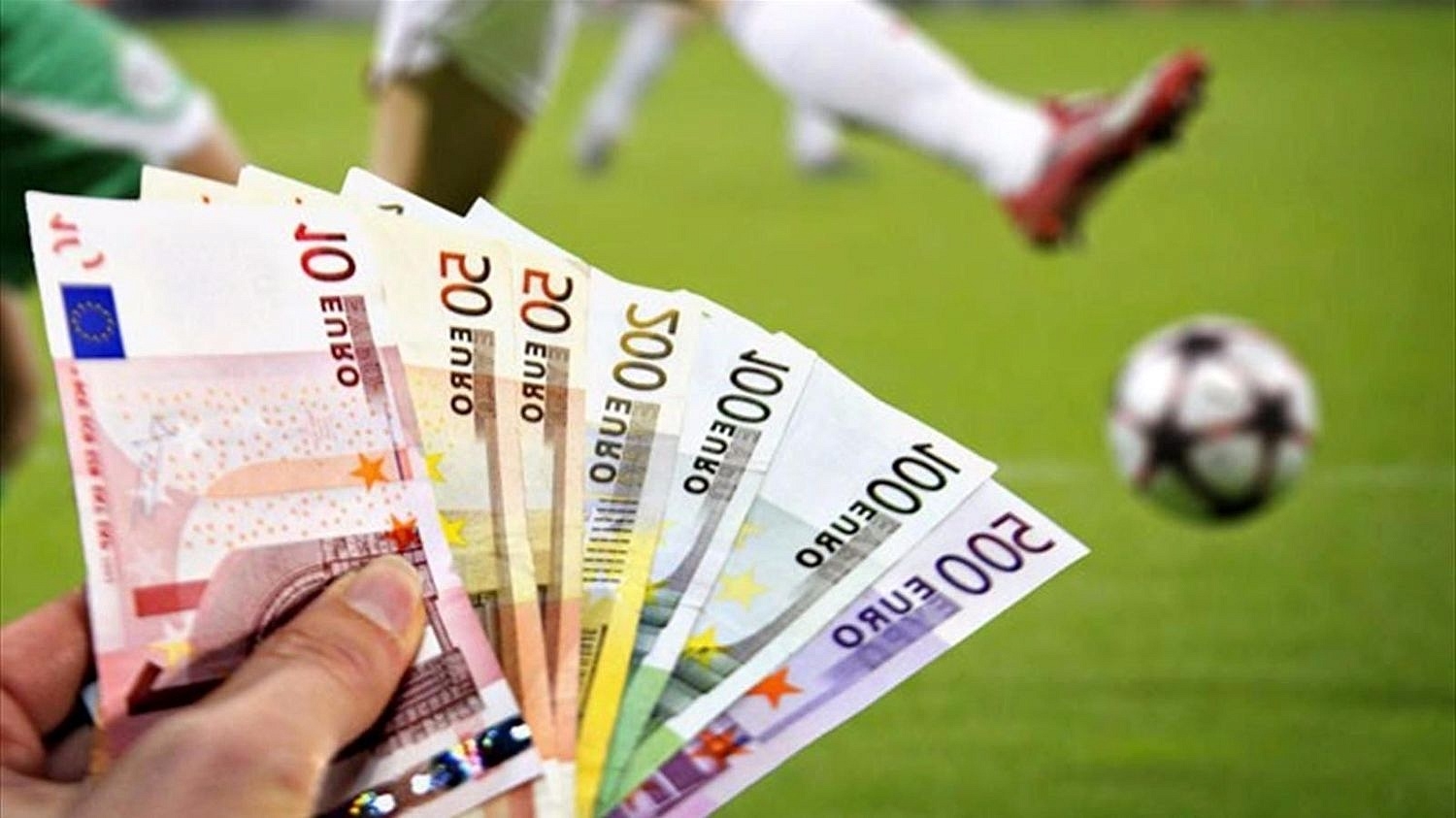 Игрок держит в руках много купюр евро, а на заднем фоне идет борьба за мяч на футбольном поле