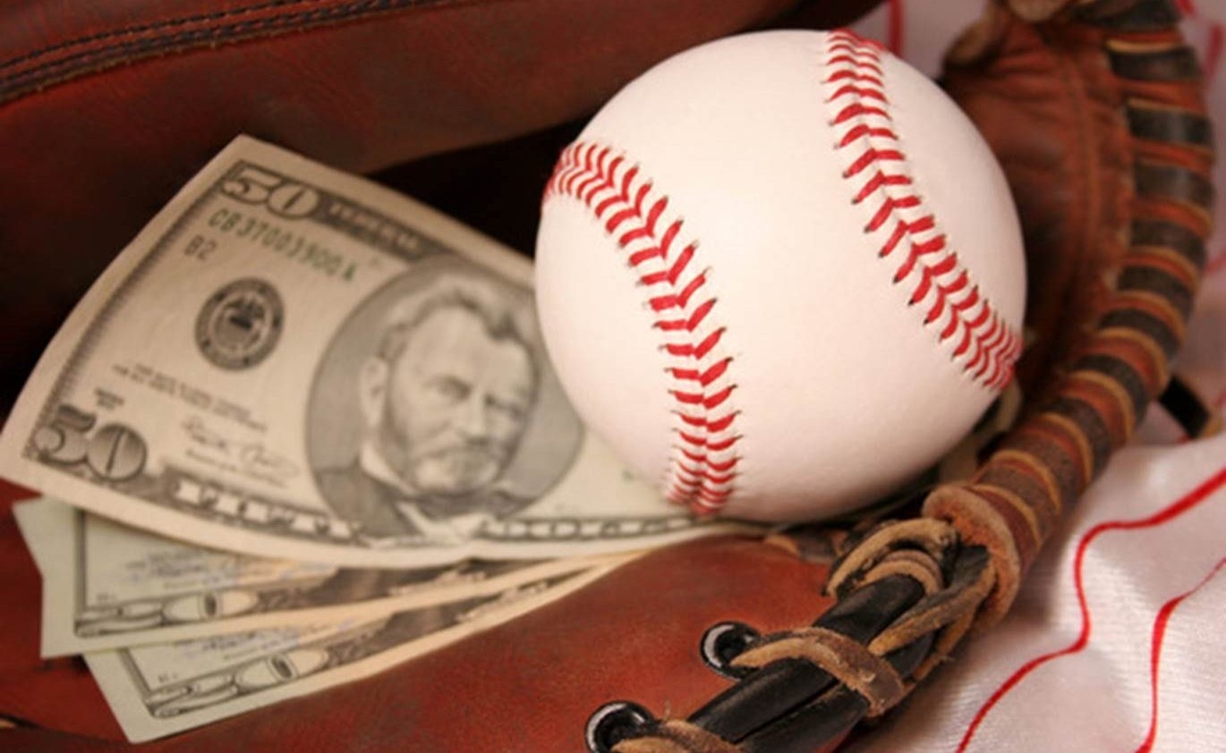 В рукавице для бейсбола лежит мяч и несколько купюр по пятьдесят долларов