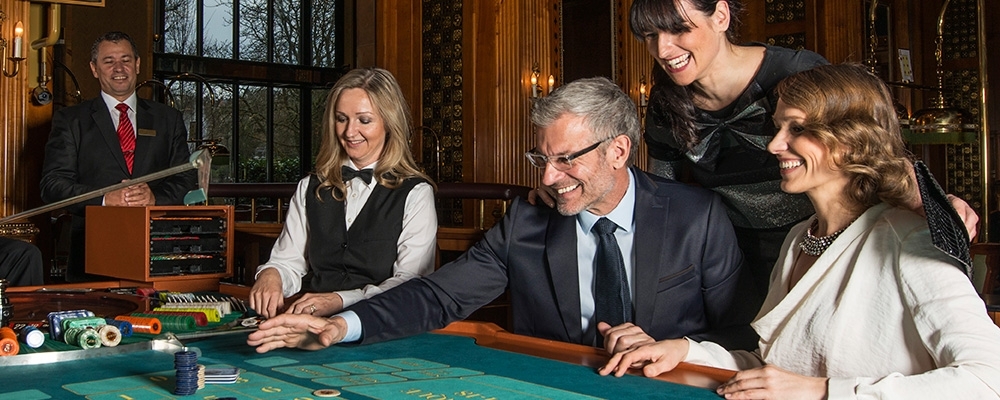 Немолодой мужчина играет в рулетку в компании двух симпатичных женщин