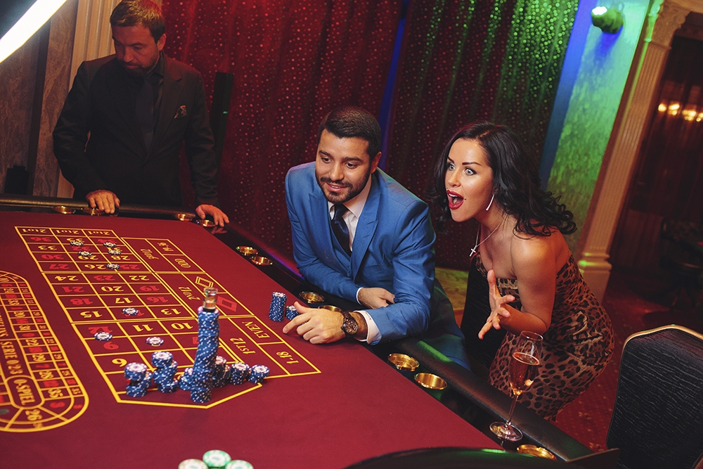Роскошная брюнетка в вечернем мини-платье с леопардовым принтом болеет за ставки своего мужчины, с которым пришла играть в рулетку в престижное казино