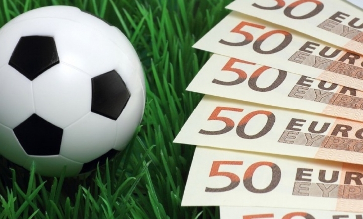 Рядом с футбольным мячем на траве разложены купюры по пятьдесят евро