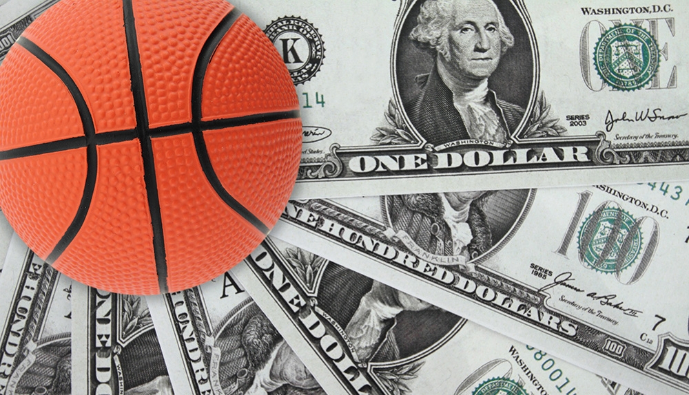 Разложены стодолларовые купюры, а сверху лежит баскетбольный мяч