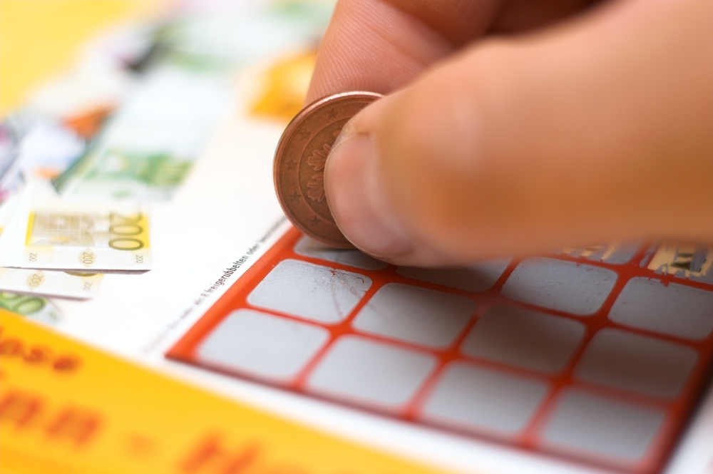 Игрок стирает защитное поле на билете мгновенной лотереи