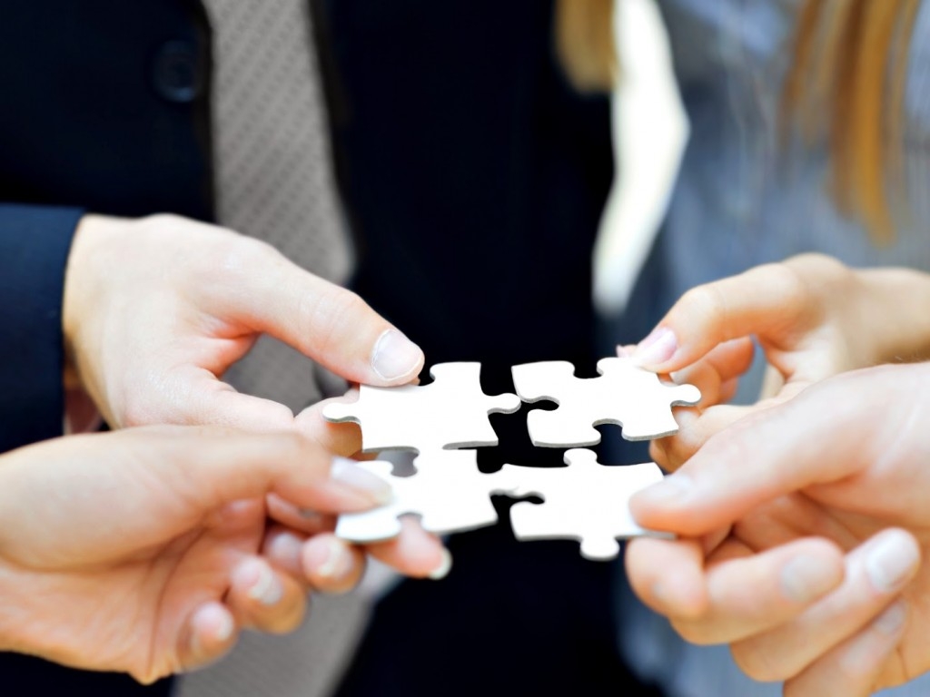 Четверо трейдеров Форекс держат в руках белые пазлы