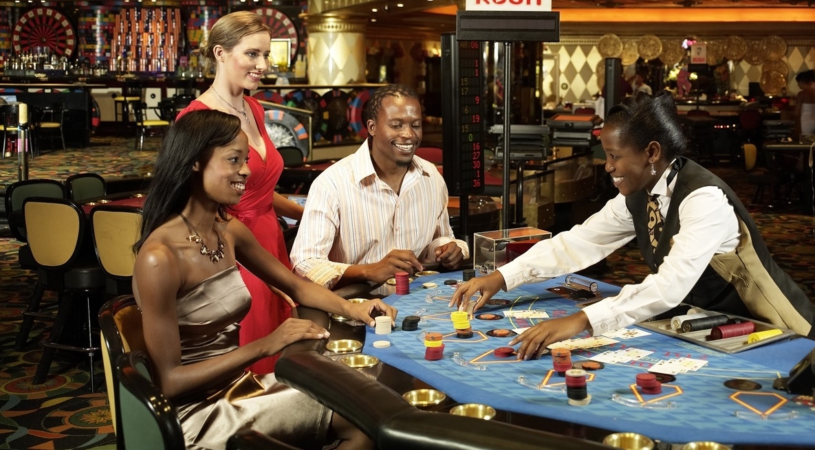 Темнокожая девушка крупье принимает ставки игроков в блэкджек