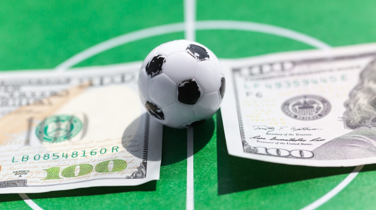 Миниатюрный футбольный мяч и две стодолларовые купюры