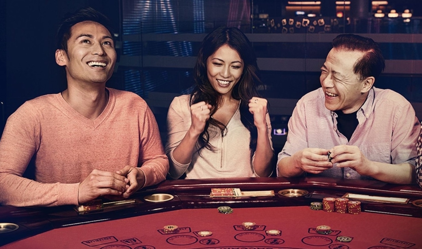 Молодая пара азиатов в компании пожилого мужчины играют в казино