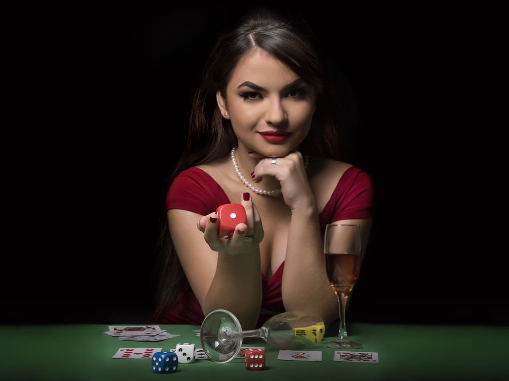 Загадочная шатенка сидит за столом в дорогом казино в полумраке