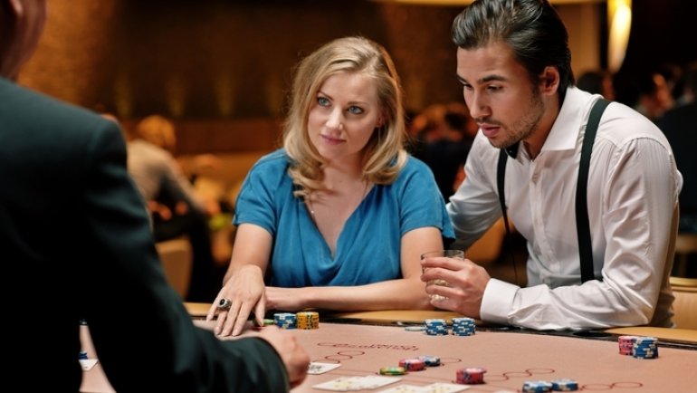 МСолодая пара за игрой в блэкджек против дилера казино