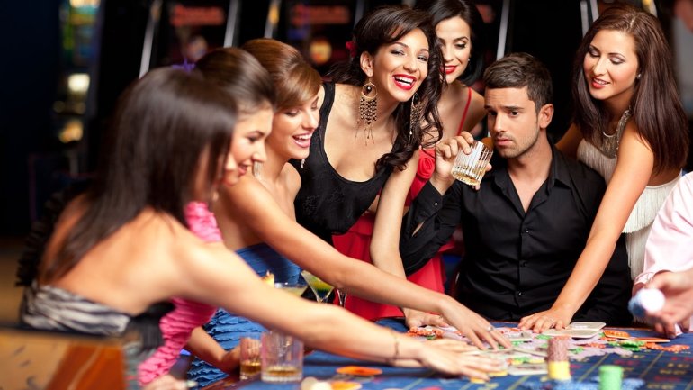 Молодой грузин пьет виски за игрой в рулетку в окружении нескольких привлекательных девушек