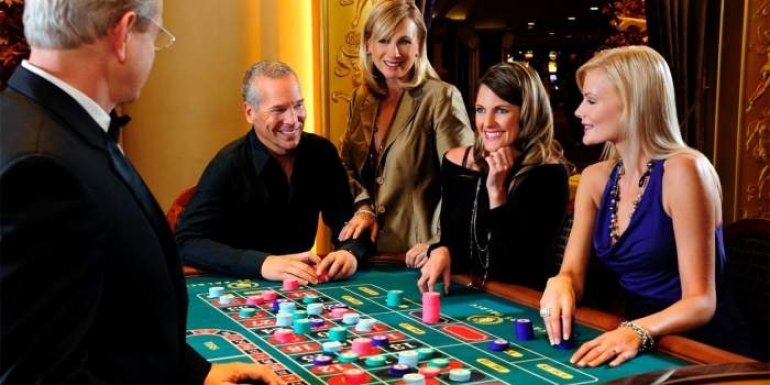 Мужчина в компании трех очаровательных дам играет в рулетку с крупье